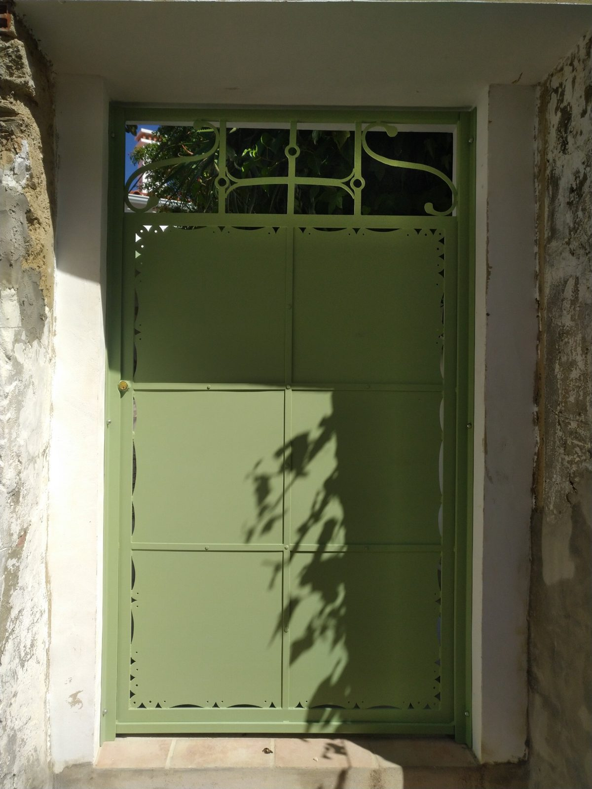 Portão em ferro pintado de verde com recortes decorativos